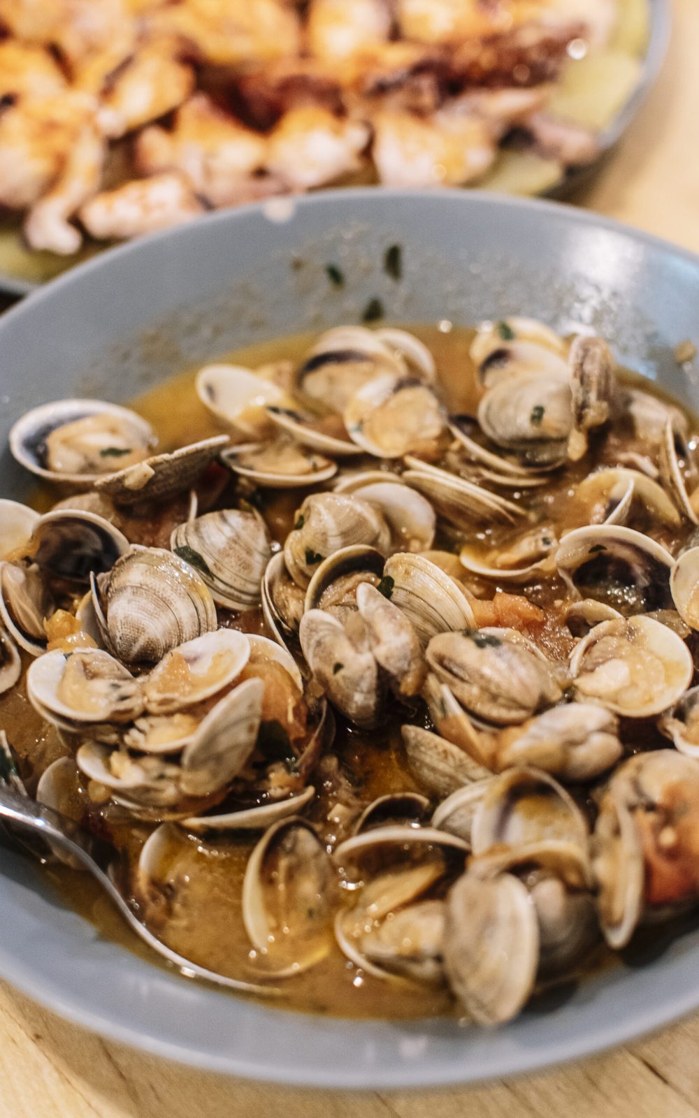Clams cooked in sauce served in a deep plate.